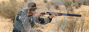 Hunting period, autumn season open. A hunter with a gun in his hands in hunting clothes in the autumn forest in search of a trophy