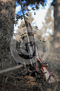 Hunting professional equipment. Hunter binoculars, rifle and Bag laid on the grass in the forest