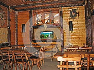 Hunting restaurant decor, wooden tables and chairs, wood walls, aquarium and deer antlers hanging on the wall