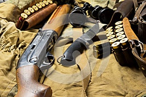 Hunting rifle and ammunition lie on wooden background.