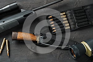 Hunting rifle and cartridges on dark wooden background