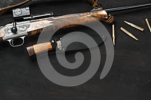 Hunting rifle and cartridges on dark wooden background