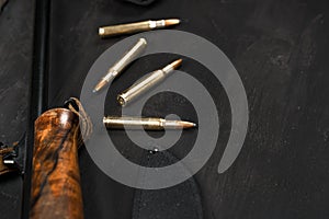 Hunting rifle and cartridges on dark wooden background