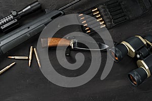 Hunting rifle and cartridges on dark wooden background