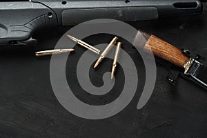 Hunting rifle and cartridges on dark wooden background