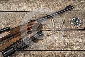 Hunting rifle and cartridges on dark wooden background