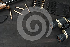 Hunting rifle and cartridges on dark wooden background