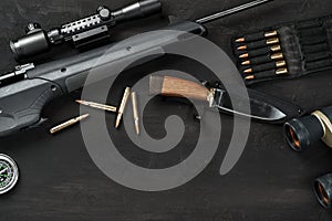 Hunting rifle and cartridges on dark wooden background