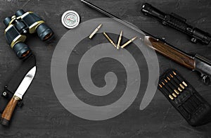 Hunting rifle and cartridges on dark wooden background