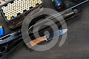 Hunting rifle and cartridges on dark wooden background