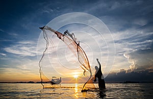 Hunting for Sunset. Silhouette of unidentified fisherman casting fishing net.