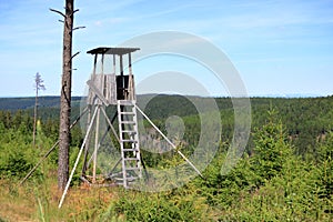 Hunting tower in the forest. Wooden Hunter Hide High watch post tower. Hunter`s observation point in forest in Europe