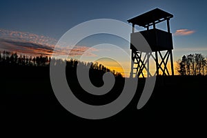 Hunting tower silhouette on sunset in blue and orange