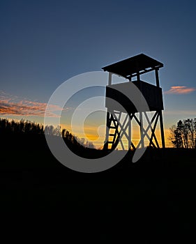 Hunting tower silhouette on sunset in blue and orange