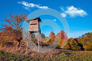 Hunting tower in wild forest. Wooden Hunter Hide High watch post tower. Hunter`s observation point in forest in Europe