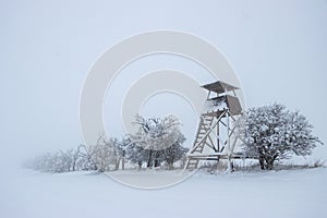 Hunting tower in winter landscape. Heavy snowing