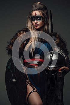 Huntress amazon with shield and helmet against grey background