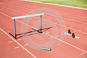 Hurdle, relay baton and a starting block kept on a running track