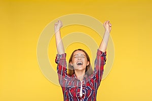 Hurray, victory! Portrait of delighted girl in checkered shirt yelling for happiness, enjoying life, rejoicing success with arms