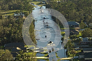 Hurricahe fainfall flooded Florida road with evacuating cars and surrounded with water houses in suburban residential