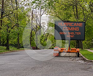 Hurricane Coming Seek Shelter warning information sign on trailer with LED face on street lined with trees