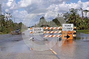 Hurricane flooded street with road closed signs blocking driving of cars. Safety of transportation during natural