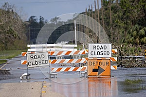 Hurricane flooded street with road closed signs blocking driving of cars. Safety of transportation during natural