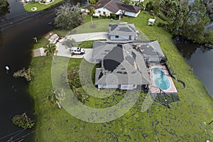 Hurricane Ian destroyed house with damaged roof and lanai enclosure over swimming pool in Florida residential area