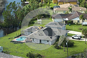 Hurricane Ian destroyed house with damaged roof and lanai enclosure over swimming pool in Florida residential area