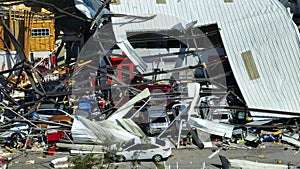 Hurricane Ian destroyed industrial building with damaged cars under ruins in Florida. Natural disaster and its