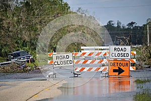 Hurricane Ian flooded street with road closed signs blocking driving of cars. Safety of transportation during natural