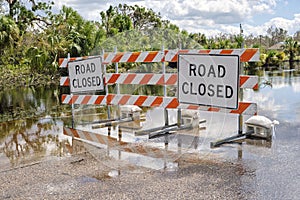 Hurricane Ian flooded street with road closed signs blocking driving of cars. Safety of transportation during natural