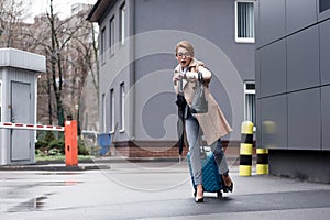 hurrying businesswoman with suitcase checking time and running