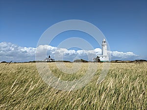 Hurst Point Lighthouse grassland and white cloud on a blue sky