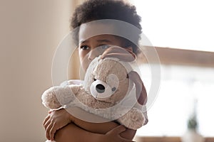 Hurt small biracial boy hold toy feeling lonely