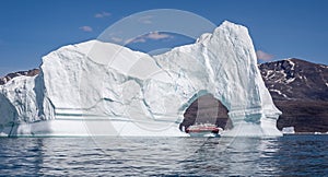 Hurtigruten`s MS Fridtjof Nansen expedition  cruise ship seen through an arch in a gigantic iceberg at Disko Bay, Greenland