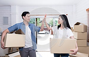 Husband and attractive wife helping each other to lift the box Happily, to move into a new home