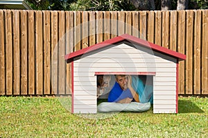 Husband or boyfriend man sleeping in the doghouse because of domestic problems