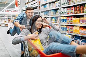 Husband carries his wife in the cart, supermarket