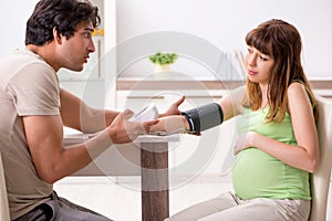 The husband checking pregnant wife`s blood pressure