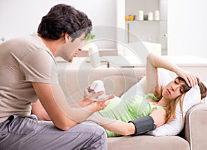 Husband checking pregnant wife`s blood pressure