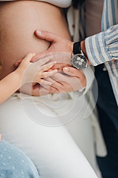 Husband and child hands on pregnant woman& x27;s belly.