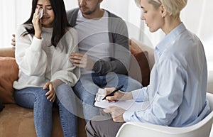 Husband Comforting Crying Wife During Session With Psychologist In Office