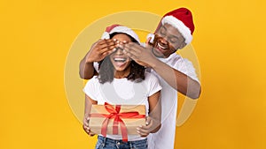 Husband Congratulating Wife On Christmas, Covering Her Eyes, Yellow Background