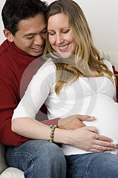 Husband embraceing his pregnant wife`s belly.