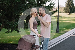 husband feeding wife with ice cream near baby carriage photo