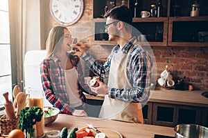 Husband feeds wife a banana on the kitchen