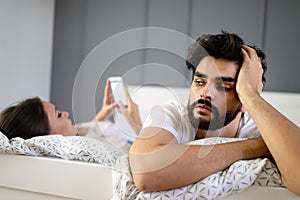 Husband is frustrated, upset while his internet addict wife is using mobile phone in social network