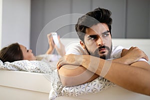 Husband is frustrated, upset while his internet addict wife is using mobile phone in social network