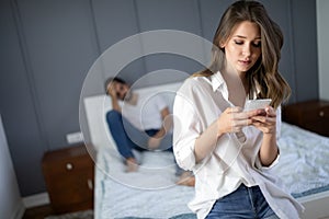 Husband is frustrated, upset while his internet addict wife is using mobile phone in social network